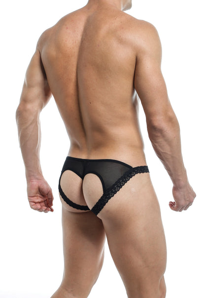 A man modeling black lace underwear with a heart-shaped cutout on the back, rear view.

